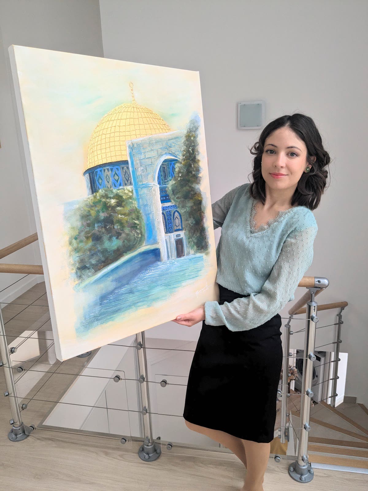 The artist carrying a large canvas of the Dome of the Rock, painted in gold and blue with a tree beside it.