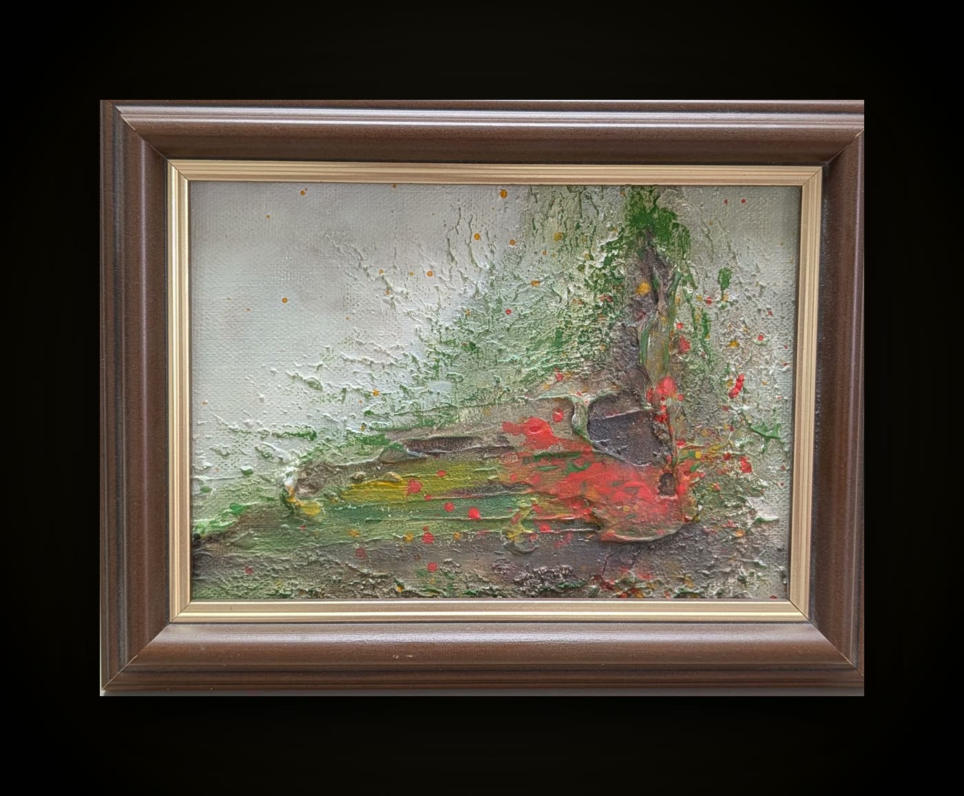 A small framed work in a dark wood frame: heavy white and green texture with red and yellow breaking through.
