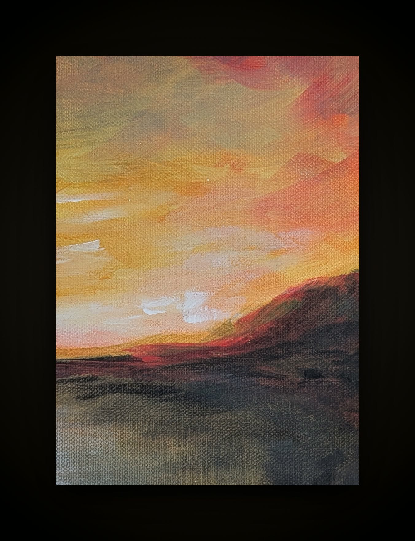 A small framed painting: a burning orange and yellow sunset over a dark ridge.